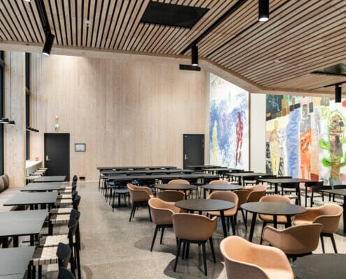 Splitkon_SporX-2 Inne i lokalet med mange sitteplasser og store malerier på vegg, foto.