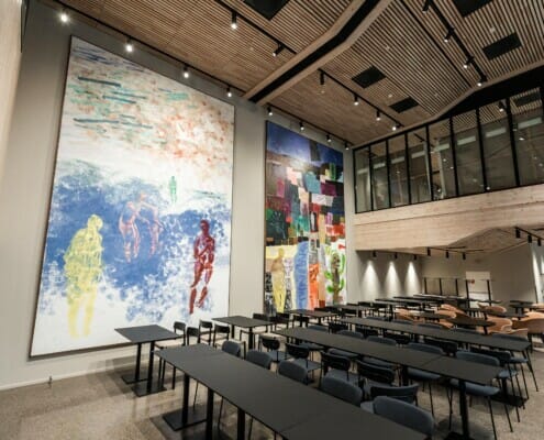 Splitkon_SporX-31 Inne i lokalet med mange stoler og bord, med store malerier på veggen, foto.