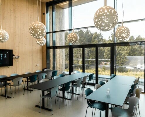 Splitkon_ModumAMB-1 Inne i kantina fylt med stoler og bord i grå toner, foto.