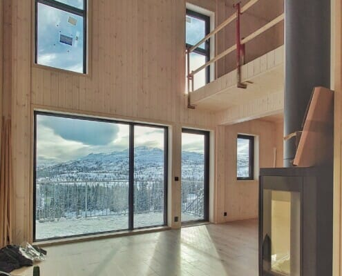 274515091_1923367804520978_1099259019950409602_n Inne i Fjellparken med peis, svarte vinduer, massivtre og utsikt om vinteren, foto.